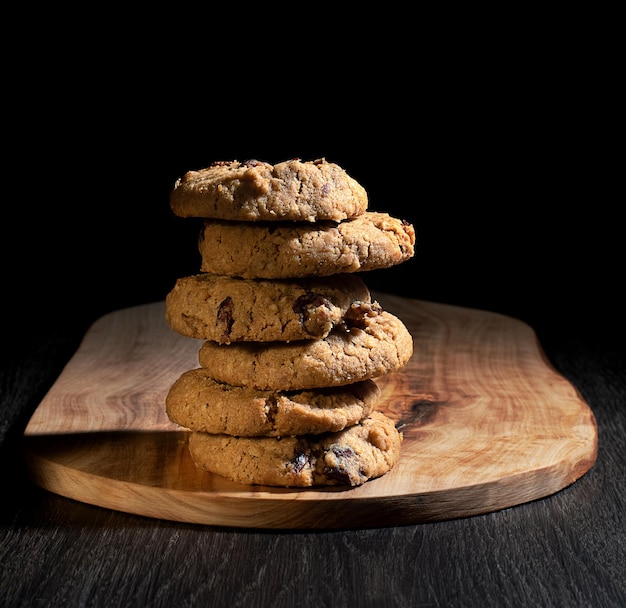 Oats cookies on wooden chopping board and black background