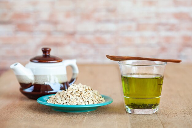 Oats flakes in wood spoon with hot green tea on wood table