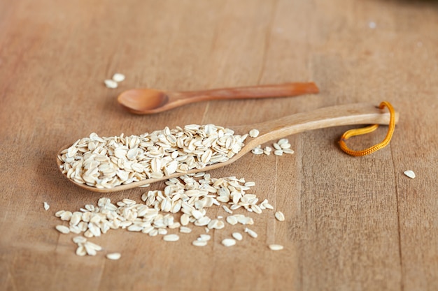 Oats flakes in wood spoon on wood table.