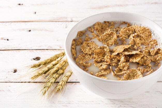 Foto latte e cereali dell'avena sulla tavola di legno bianca