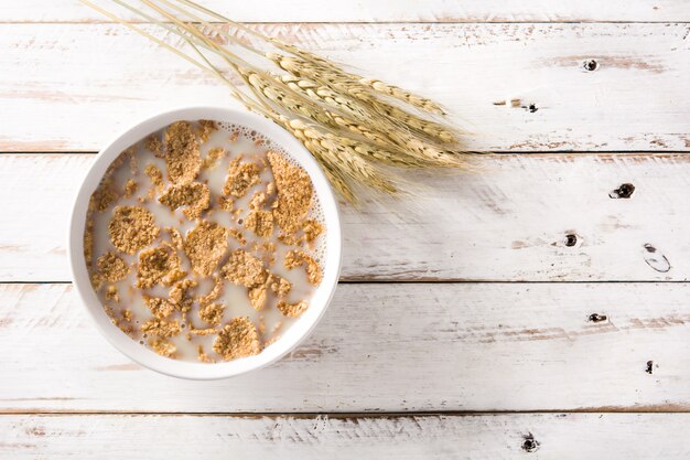 Foto latte e cereali dell'avena sulla tavola di legno bianca