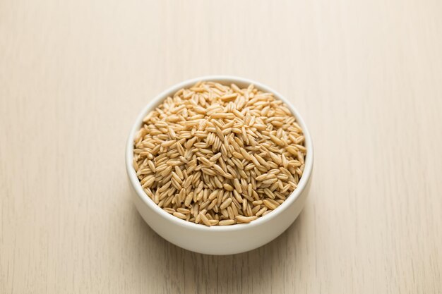 Photo oats in a small white bowl on a wooden table