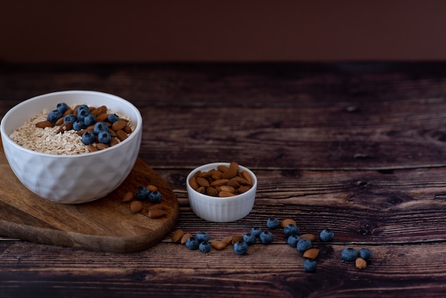 Oats in a spoon in a plate on a table scattered oat flakes.