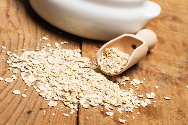 Oats in a white bowl with a wooden spoon