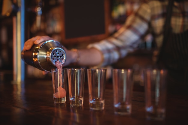 Ober cocktail drinken gieten in borrelglaasjes aan balie