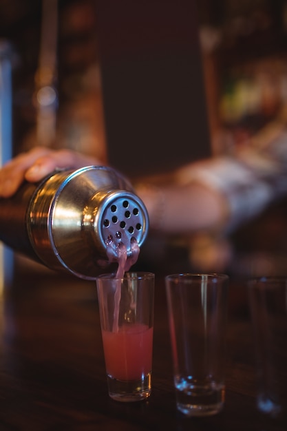 Ober cocktail drinken gieten in borrelglaasjes aan balie