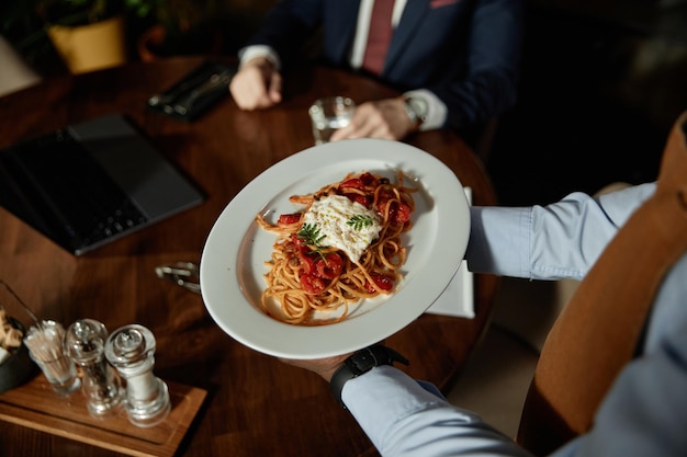 Ober die pasta serveert aan de klant