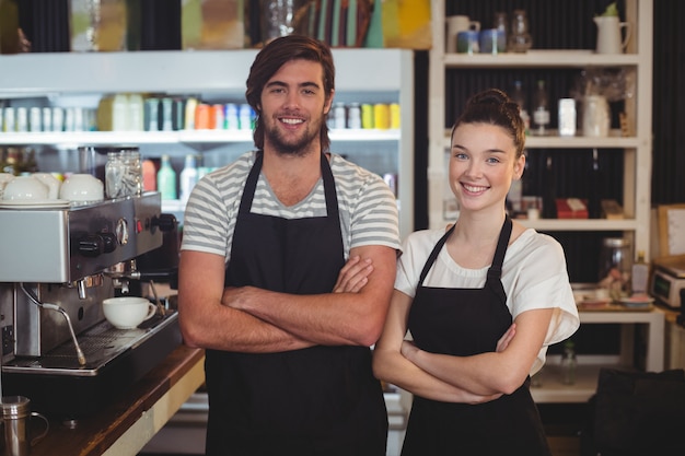 Ober en serveerster permanent met armen gekruist in café