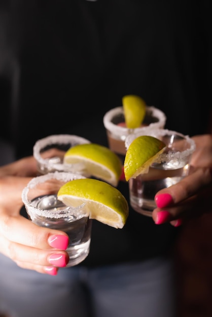 Ober meisje heeft vier alcoholische shots versierd met citroenen in haar handen De barman bereidt drankjes voor gasten Nachtleven clubleven Geweldige portie cocktails Geweldige cocktails