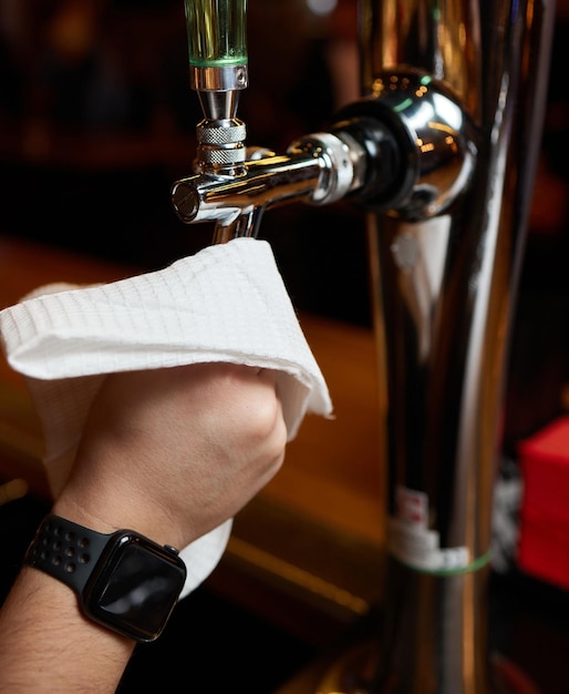 Foto ober of barman die bierkranen op de toonbank in pub en restaurant schoonmaakt