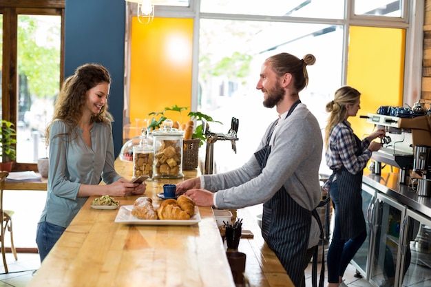 Ober serveren een kopje koffie aan de klant aan balie