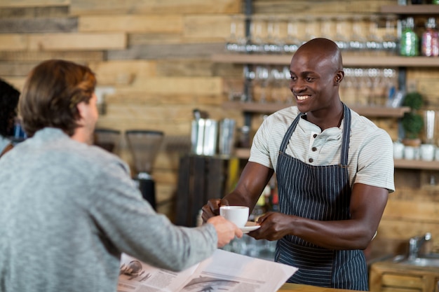 Ober serveren kopje koffie aan man aan balie