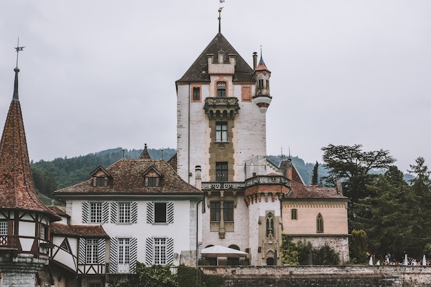 Oberhofen, svizzera - 22 giugno 2017: vista sul castello di oberhofen - museo vivente e parco dalla nave, svizzera, europa. paesaggio estivo, tempo nuvoloso, cielo drammatico e giornata di sole