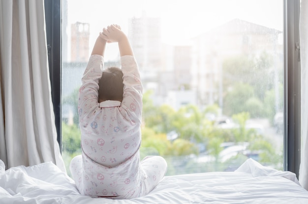 写真 パジャマの肥満な太った男の子がベッドに座っている