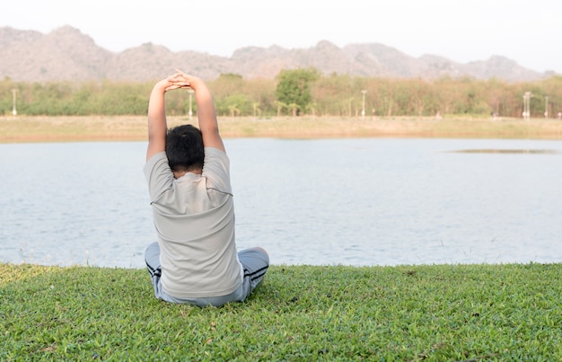 obese fat boy play yoga or exercise on green grass.