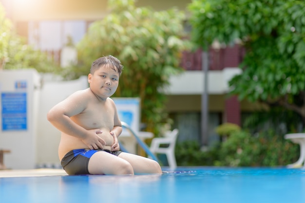 肥満太った少年がプールに座る