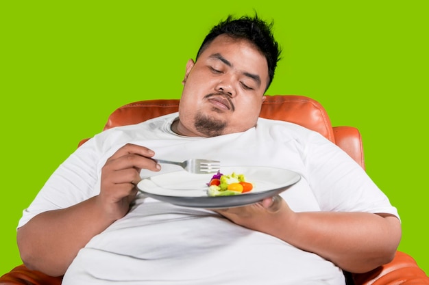 Obese man looks lazy to eat food on studio