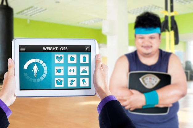 Obese man with scale and app of weight loss | Premium Photo