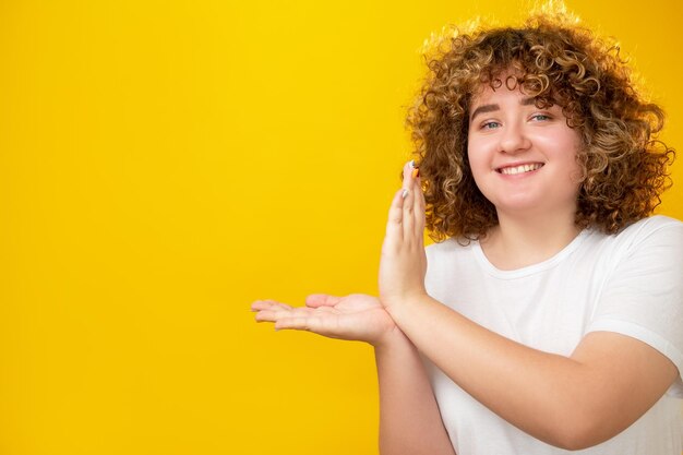 Obese people special offer advertising background good diet happy joyful overweight young woman with curly hair open palms pointing on yellow copy space