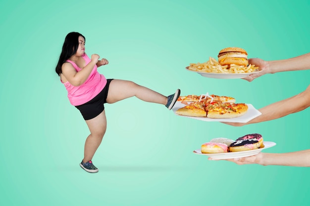 Obese woman kicking unhealthy foods