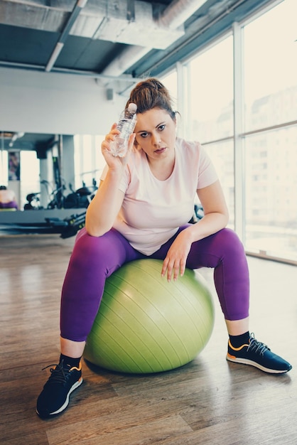 Photo obese woman sits on gym ball in gym