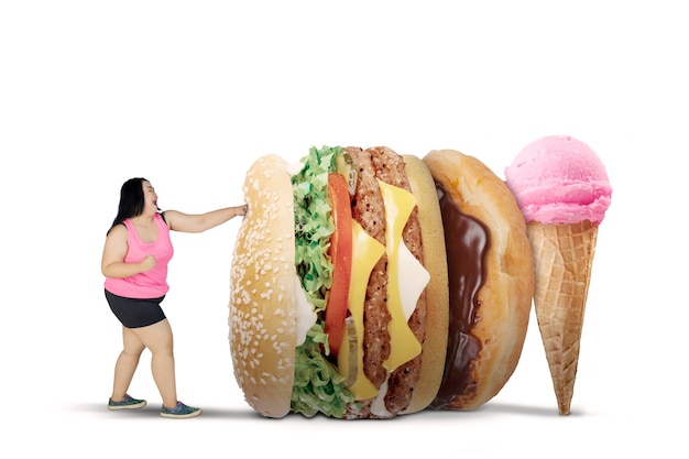 obese woman wearing sportswear while fighting with unhealthy foods, isolated on white background
