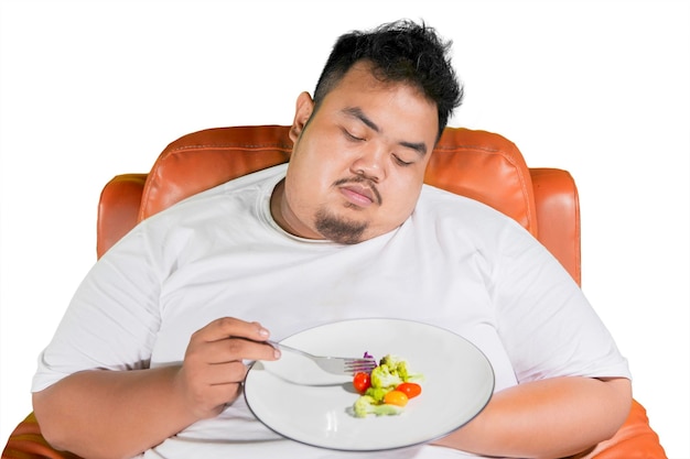 Obesitas man ongelukkig uitdrukken tijdens het eten van salade