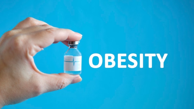 Obesitastekst in de hand van een man die een flesje vasthoudt met een remedie voor genezing