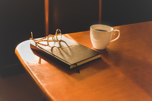 Objecten koffie en brillen met dagboek op tafel.