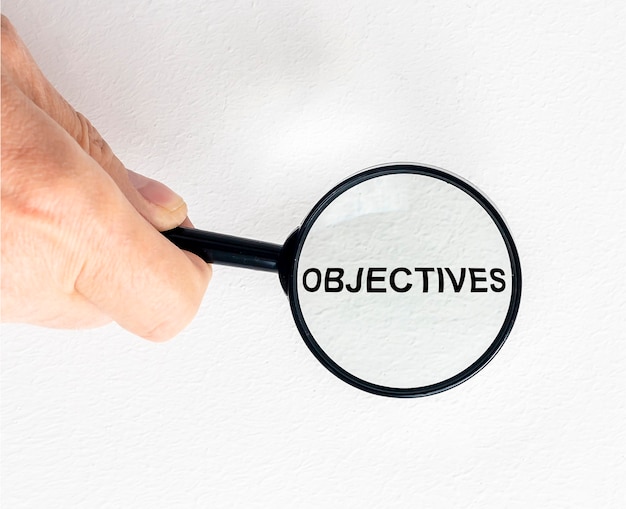 Objectives word inscription through magnifying glass on financial documentss, business goals.