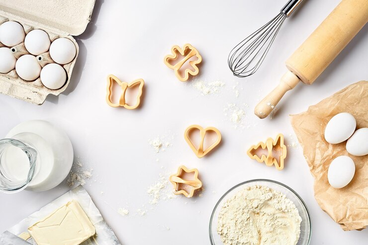 Photo objects and ingredients for baking plastic molds for cookies on a white background flour eggs rolling pin whisk milk butter cream top view space for text