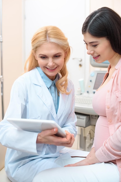 Obstetrician gynecologist and pregnant woman using tablet together