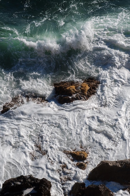 Oceaangolfachtergrond die de rotsachtige kust van het zeewater breekt