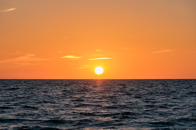 Oceaanzonsondergang Grote witte zon op dramatische heldere hemelachtergrond zachte avondwolk over overzees donker water