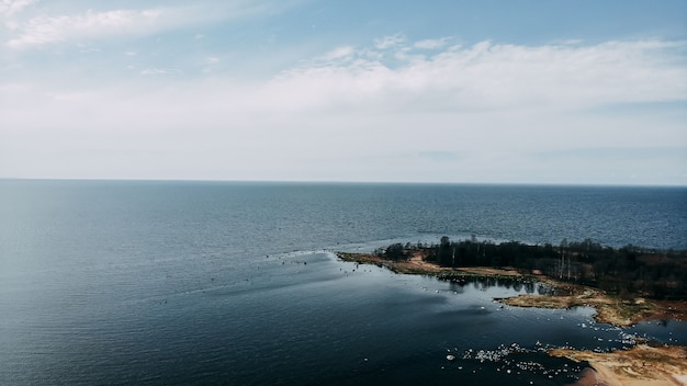 Ocean shore view from quadcopter, sand and rocks on the sea coast. Ocean shore top view. Horizon and blue water.