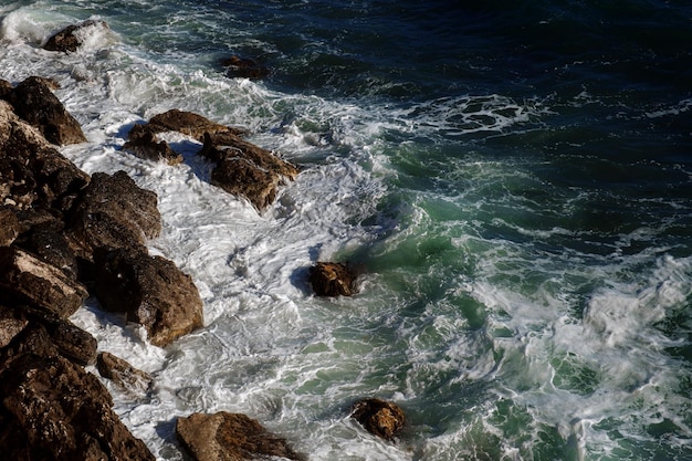 海水の岩の多い海岸を壊す海の波の背景