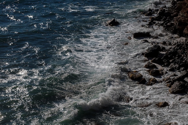 海水の岩の多い海岸を壊す海の波の背景