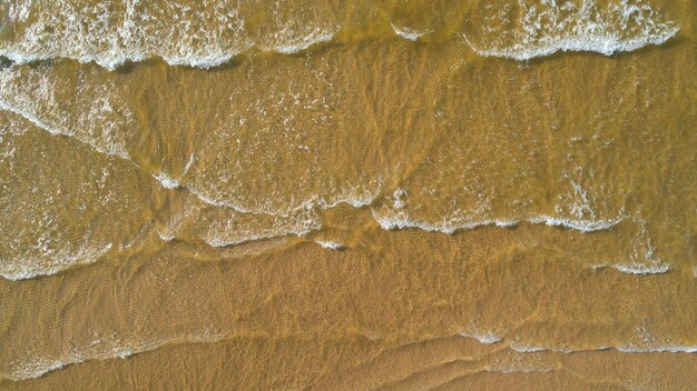 Foto ondate dell'oceano sulla spiaggia come sfondo belle vacanze estive naturali sfondo vista aerea dall'alto verso il basso della spiaggia e del mare con onde d'acqua blu