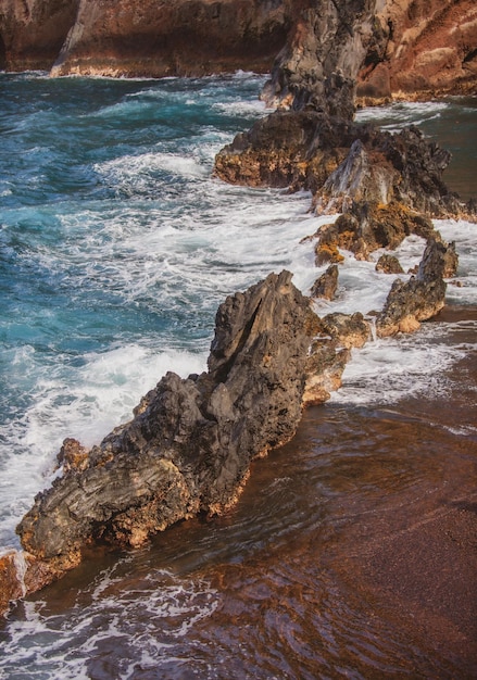 Ocean waves crashing on the rocky island coast splashing ocean waves and stones red sand beach maui ...