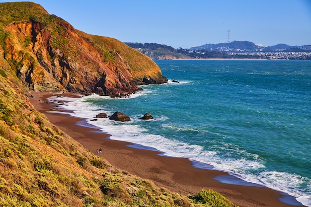 Ocean waves crashing on sandy beaches of west coast next to hills