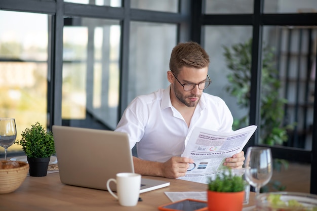 Ochtend aan het werk. Een geconcentreerde man leest een krant op zijn werkplek