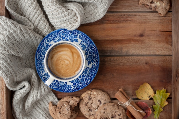 Ochtend geurige en houten achtergrond. Koekjeskoekjes met chocolade als ontbijt en een warme gebreide plaid. Herfst decoratie. Bovenaanzicht. Kopieer ruimte