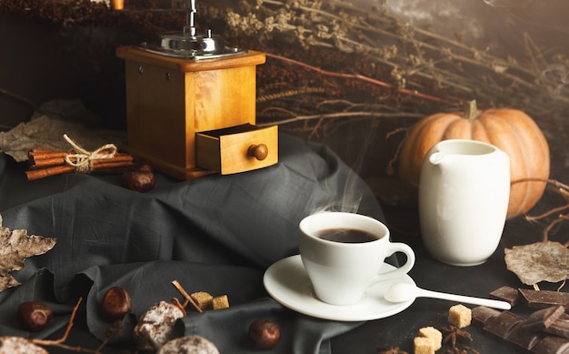 Ochtend herfst koffie achtergrond. Kopje americano, melkpot, vintage molen, droge persimmon, pompoen, vario en geraffineerde suiker op rustieke tafel, kopieerruimte