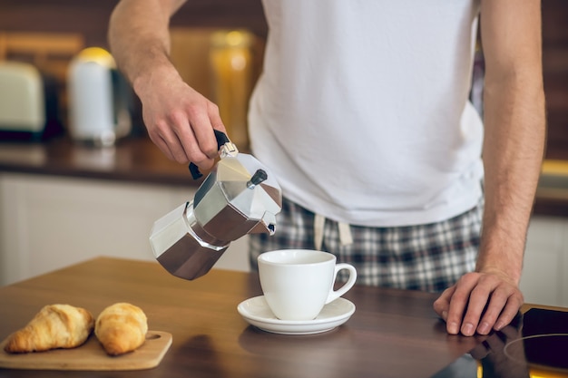 Ochtend koffie. Close up van man in homewear koffie gieten naar de beker