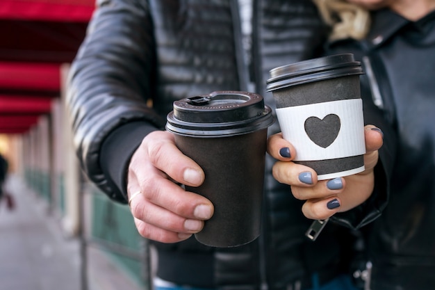 Ochtend koffie. Vrouw en man hebben een wegwerpkoffiekopje met een gehoorde vorm op glas. Hoge kwaliteit foto