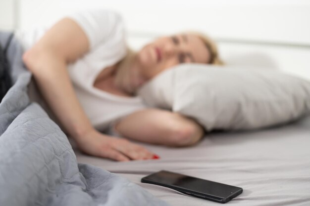 Ochtend met gadget. overhead van mooie jonge vrouw liggend op de bed-smartphone. bovenaanzicht.