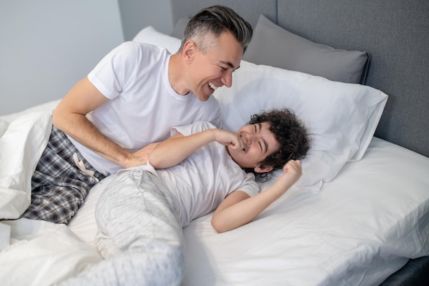 Ochtend plezier. Vader en zoon hebben 's ochtends plezier in bed en zien er vrolijk uit