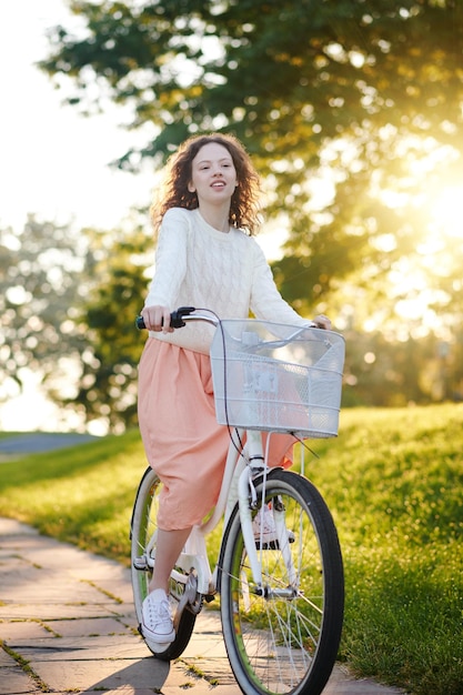 Ochtend rit. Meisje in roze rokje met een fiets in het park