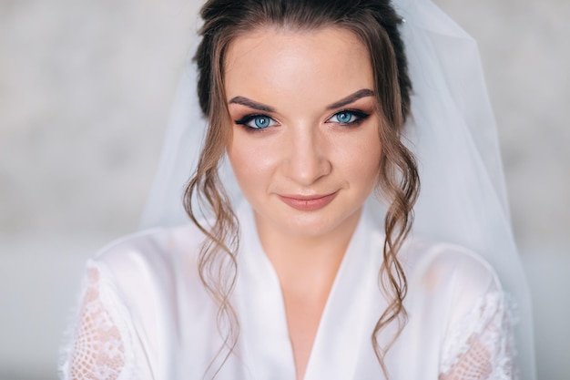 Ochtend van de bruid voor de bruiloft mooie vrouw met lang haar in een wit gewaad natuurlijke schoonheid en professionele make-up