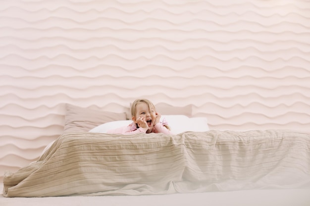 Ochtend van klein meisje in een comfortabele slaapkamer Gelukkig kind meisje met plezier en speelt in bed